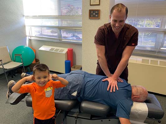 Chiropractor Falls Church VA Michael Armellino Adjusting Patient And Child